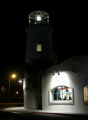 the Carrillo Street Lighthouse sends out its beacon in the night while patrons eat pizza inside